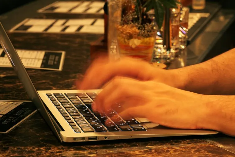 カウンターでノートPCのキーボードを打つハッカーの手元